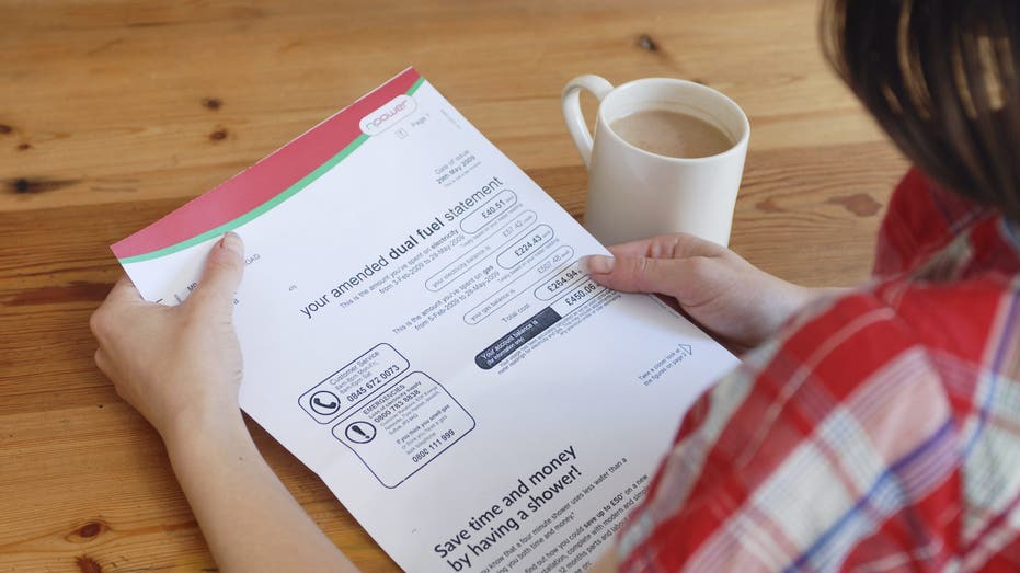 Young adult looks at utility bill with coffee